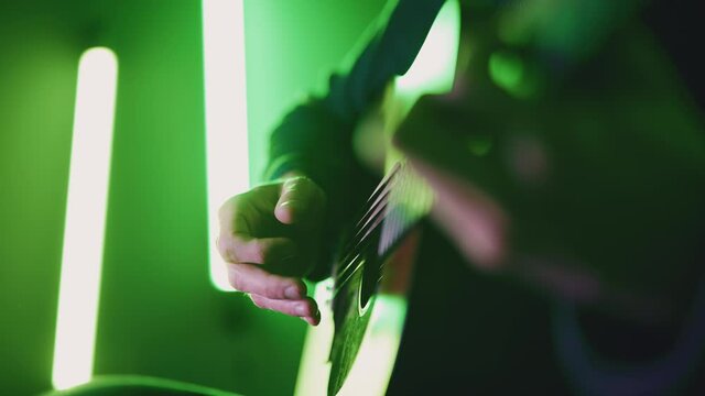 Musician playing acoustic dreadnought guitar with atmospheric coloured lighting