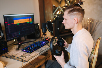 Young happy dj man wearing headphones and working at home while making podcast recording for online show