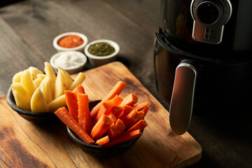 Cooking potatoes and carrot sticks with spices in an air fryer