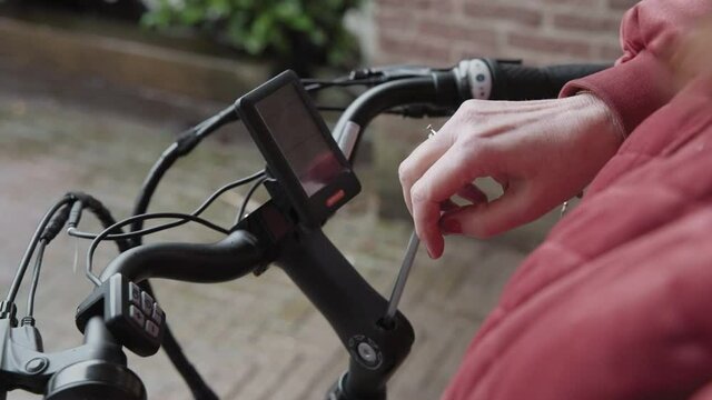 Lady adjusting a allan key bolt to be able to change the angle of the handle bars on her Electric bike.