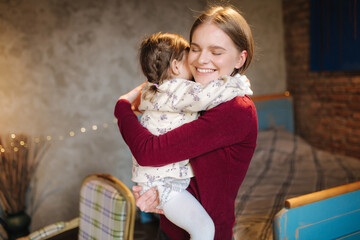Adorable little girl hug her beautiful and young godmother. Portrait of happy woman hug her...
