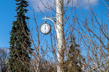 A round street clock with hands shows the time one minute past one. 12.01.