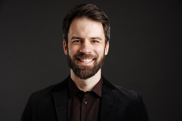 Bearded happy man in black jacket smiling and looking at camera