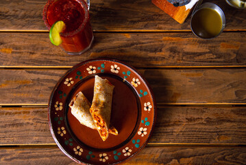 Mexican burrito and michelada beer with tomato juice with copy space. Michelada beer with tomato juice and burritos. Mexican food on wooden table. Concept of traditional food and mexican drink.
