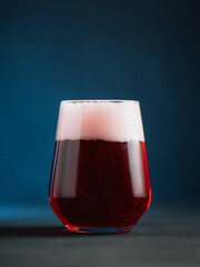 A glass of craft beer on a dark blue background, close-up vertical photo.
