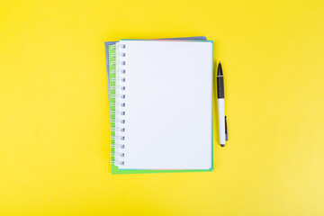 open spiral notepad on a yellow background with a pen. top view, stack of notepad with blank sheet. school concept, businessman work