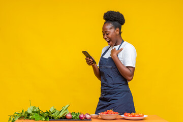 female african chef looking excitedly at her phone