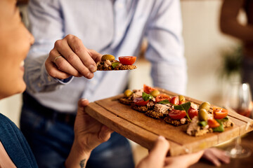 Close-up of woman serving  healthy bruschetta  to her husband at home.