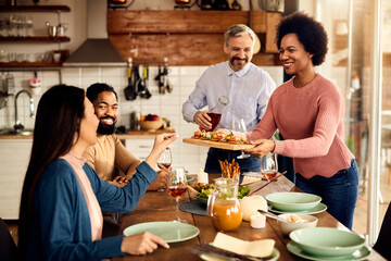 Multi-ethnic group of friends having lunch at dining table at home.