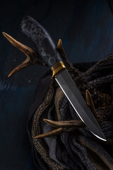 Handmade hunting knife made of Damascus steel lies on the horns