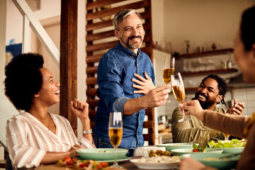 Happy man holding a toast while having lunch with his friends at home.