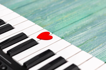 Piano keyboard with little red heart on a wooden green background