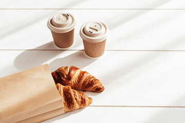 Hot coffee on the go and croissants for breakfast. Biodegradable, disposable takeaway coffee and tea cups, eco friendly alternative lifestyle