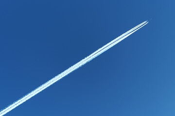 Vierstrahliges Flugzeug mit weißen Kondensstreifen  als Diagonale und blauer Himmel - Stockfoto