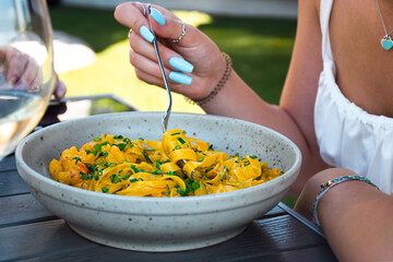 Young woman eating pasta at an outdoor restaurant patio