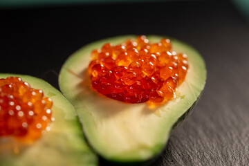 Red caviar served in half a green avocado close-up. Healthy food concept