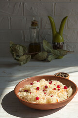 Sauerkraut with cranberries in a brown clay plate on a wooden background. Fermented vegetables. Super product for proper nutrition.