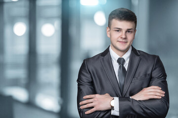 Obraz premium Businessman with arms crossed stands on blurred background.
