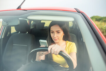 Woman reads from a smartphone while sitting in the car.