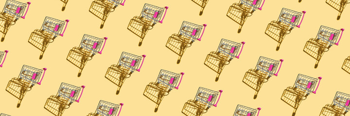 Many same shop trolley on yellow bright background. Modern mall concept. Top view repeat layout. Market cart trend wallpaper. Flatlay. Supermarket empty accessory