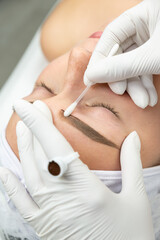 Proces makijażu permanentnego. Kobieta w salonie urody w trakcie zabiegu pigmentacji brwi.  - obrazy, fototapety, plakaty