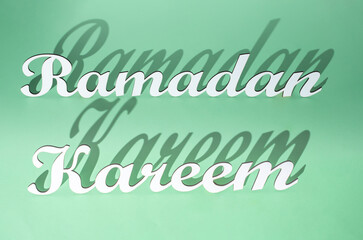 Creative Ramadan Kareem greeting card concept made of carved white 3d  letters ona a light green background. Flat lay minimal design.