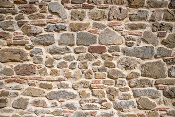 A portion of wall made of stones of different shapes and materials. Stones texture to be used as a background.