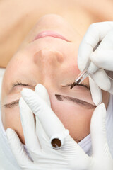 Zbliżenie na twarz kobiety w trakcie zabiegu makijażu permanentnego. Proces tatuowania brwi. 