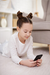 childhood, technology and internet concept - cute preteen girl using smartphone at home