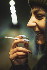 Obraz premium A girl smokes a cigarette on the street in an underground passage at night