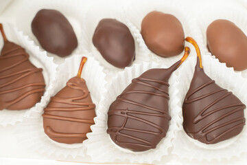 Dried fruit in chocolate: dried pear, peach in chocolate glaze on white background