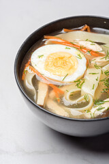 Thai soup with egg, vegetable in black bowl