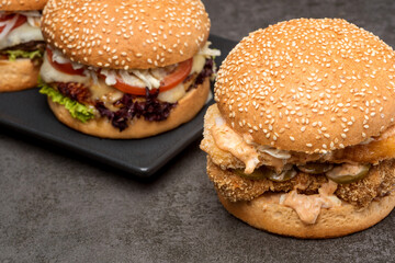 Two burgers with potatoes on the dark background