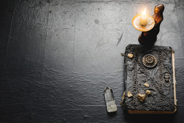 Ancient magic book and burning candle on the table close up. The witchcraft concept.