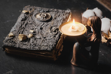Ancient magic book and burning candle on the table close up. The witchcraft concept.
