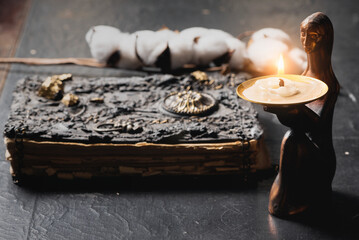 Ancient magic book and burning candle on the table close up. The witchcraft concept.