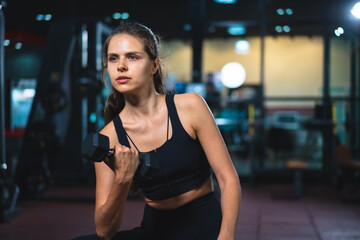 Fototapeta na wymiar Caucasian young woman in sportswear lifting dumbbell in fitness club or gym.