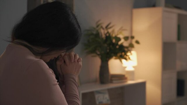 Shot from behind of praying woman at her home