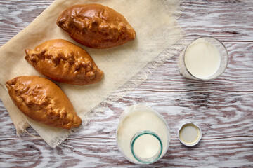 Fresh cow milk and homemade pies on wooden table, breakfast concept, close up