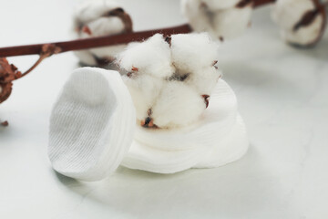 Cotton makeup disks and flowers on light background