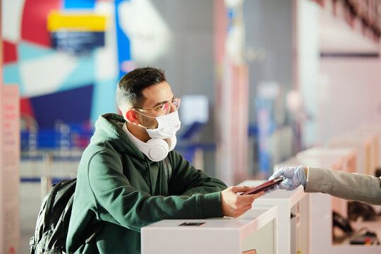 Young Man In Casualwear And Protective Mask Taking Back His Passport After Registration Before Flight At The Check Desk In Airport