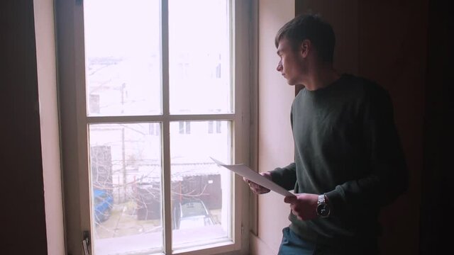 The guy examines the documents near the window. Focus of Attention reasoning. Looks out the window, looking for inspiration.