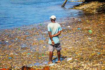 A man stands in the garbage at sea on Wasini island, Kenya. They are plastics in the Indian Ocean,...