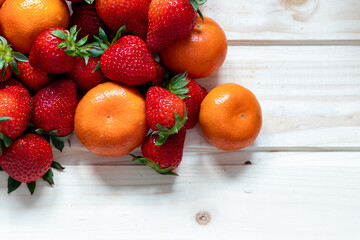 Fruits on a wooden background, strawberries picked from the garden and clementines photographed from above. The concept of healthy eating, dietary and vegetarian. Copy space