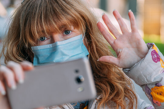woman with mask talking on mobile phone on video call
