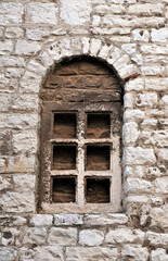 Fototapeta na wymiar Decorative antique stone window built into the stone wall