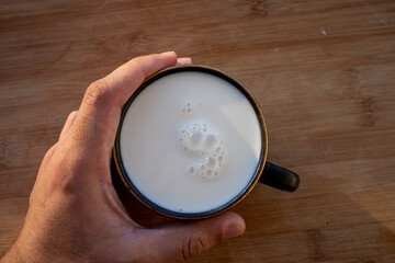 Glass of milk standing on old wooden table. Black glass with white milk. Black glass with white milk on the table