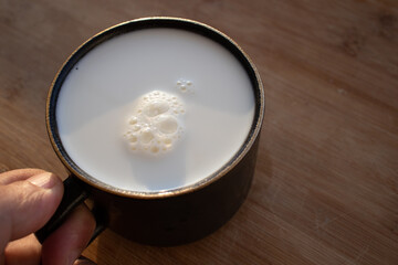 Glass of milk standing on old wooden table. Black glass with white milk. Black glass with white milk on the table