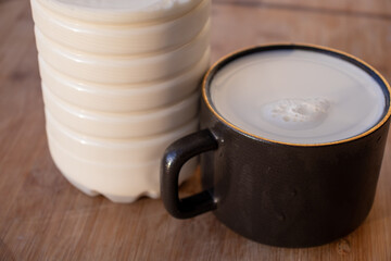 Glass of milk standing on old wooden table. Black glass with white milk. Black glass with white milk on the table