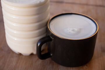 Glass of milk standing on old wooden table. Black glass with white milk. Black glass with white milk on the table